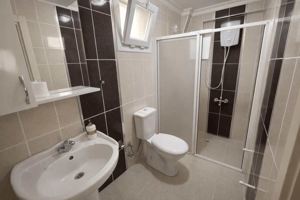 Modern bathroom featuring a shower, toilet, and sink with tiled walls.